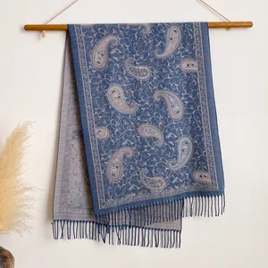 Detail van blauwe en zilveren paisley sjaal met franjes aan houten hanger