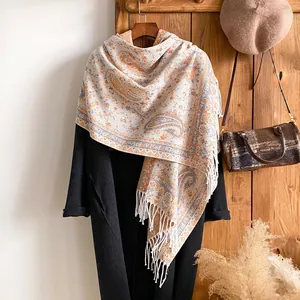Dettaglio di uno scialle con motivo paisley retrò e frange su cappotto nero