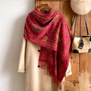 Detailopname van de rode paisley sjaal met franjes op een beige winterjas