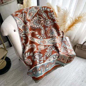 Elegant paisley print shawl with fringe tassels in brick red and blue on a chair