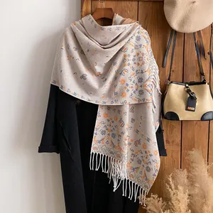 Close-up of beige floral shawl with blue and orange retro patterns and white fringe