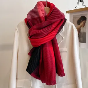 Close-up of pleated striped scarf in red and black on a white coat for winter