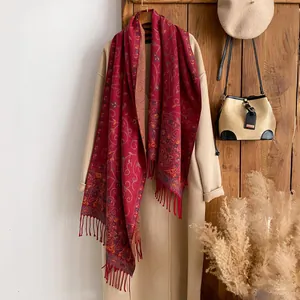Detail of red floral scarf with bohemian patterns and fringe tassels on a beige coat