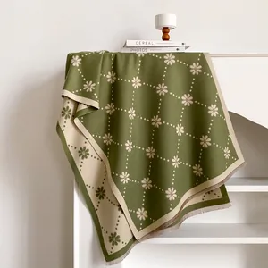 Vue détaillée du motif floral en tricot doux et des franges élégantes de l'écharpe verte