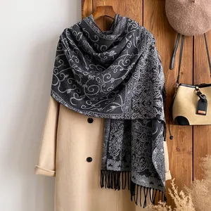 Detail of floral paisley pattern and black tassels on a long winter scarf draped on a coat
