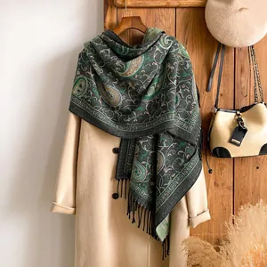 Detailopname van een paisley kasjmier sjaal met lange zwarte franjes op een wollen jas