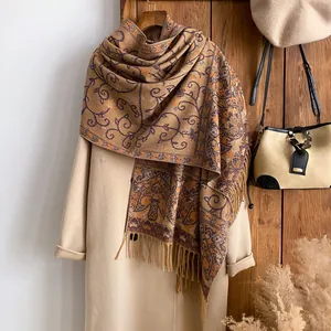 Detail of bohemian paisley scarf with long tassels against a rustic background