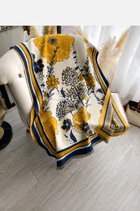 Detail of soft cashmere-like scarf showing yellow floral print and fringe edges