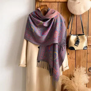 Detail van paarse paisley sjaal met fijne franjes over een beige wollen jas