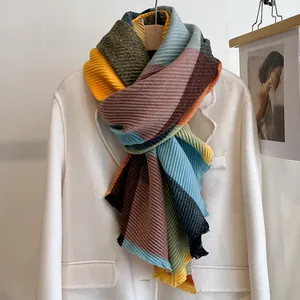 Detail of pleated striped scarf with yellow and blue color blocks on a white blazer