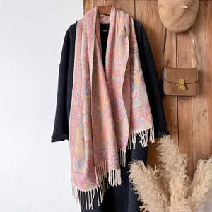 Detailed view of bohemian paisley jacquard shawl with tassels on a dark coat background