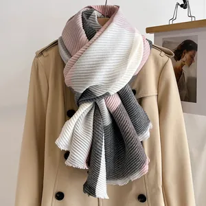 Detail of multi-color pleated winter scarf with textured pink and grey blocks on a beige coat