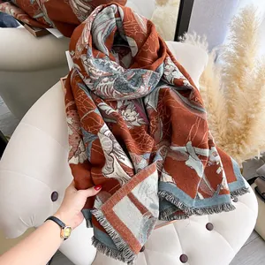 Close-up of floral cashmere feel shawl with terracotta orange base and fringe detail