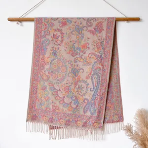 Detail of bohemian paisley shawl with tassel fringe hanging on a wooden wall rack