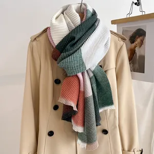 Detail of pleated scarf with accordion folds and multi-color patchwork on a beige coat