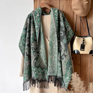 Close-up of ethnic paisley pattern and black tassels on a green bohemian cotton shawl