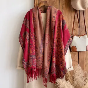 Close-up of vintage red paisley cashmere shawl with tassels on a beige coat