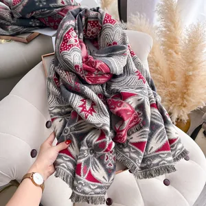 Detailansicht eines Schals mit grau-rotem Boho-Muster und feinen Fransen auf dem Stuhl