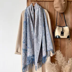 Detail of navy and silver paisley jacquard scarf with fringe on a beige wool coat
