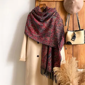Détail du châle pashmina à motif cachemire avec franges sur un manteau beige