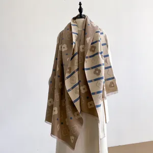 Detail of a thick double-sided cashmere-like scarf with floral patterns and soft fringe