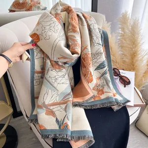 Detail of floral cashmere-like scarf with orange botanical print and fringe tassel edge