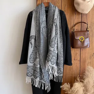 Detailed macro view of retro paisley pattern and white fringe tassels on thick shawl scarf