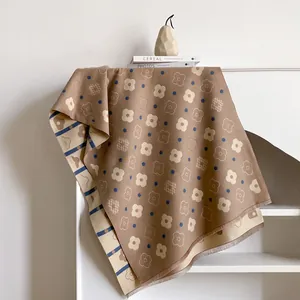Close-up of double-sided floral cashmere scarf with delicate tassel edges on a shelf