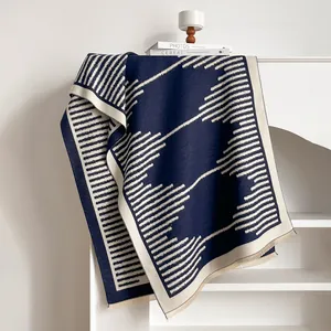 Detail of navy and beige geometric knit throw blanket with soft fringe edges