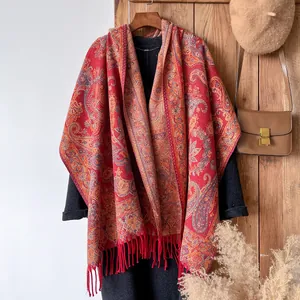Close-up of red and orange paisley cotton shawl with tassels on a dark grey wool coat