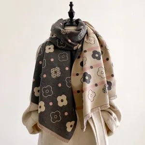 Close-up of thick double-sided cashmere-like scarf with floral patterns and soft tassels