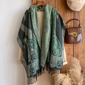 Detail of dark green paisley cashmere-like shawl with elegant fringe on a wool coat