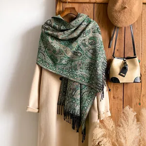 Détail d'écharpe verte à motifs paisley avec franges sur un manteau d'hiver