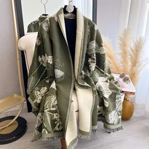 Detail of olive green cashmere-like scarf with white floral patterns and tassel fringe
