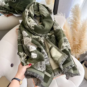 Detail of dark green floral jacquard scarf with elegant fringe trim on a chair