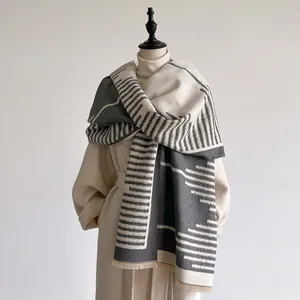 Detail of grey and white cashmere-like scarf with geometric stripes and fine fringes