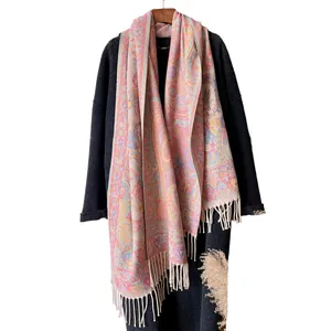 Colorful paisley jacquard cotton shawl with tassels on a coat with wooden hanger