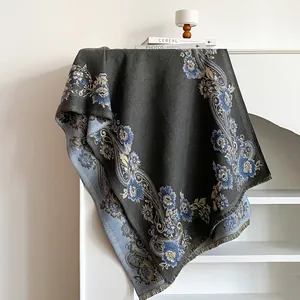 Detail of dark grey scarf with blue floral paisley patterns and tassel edges