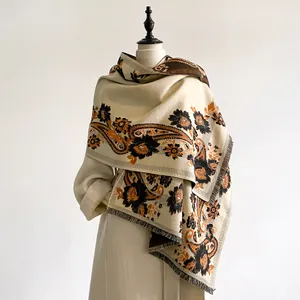 Detailed view of beige paisley cashmere scarf draped over a classic wool coat