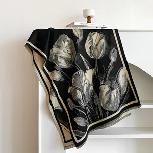 Detailed view of knitted black scarf with white tulip patterns and fringed edges