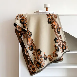 Detailed view of bohemian floral paisley patterns and tassel edges on a warm beige shawl