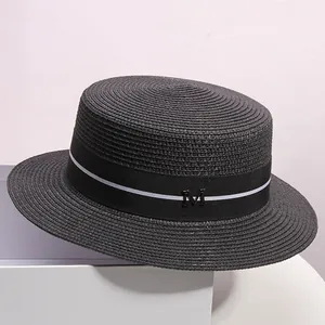 Detail of black boater hat featuring a woven texture and decorative M logo ribbon