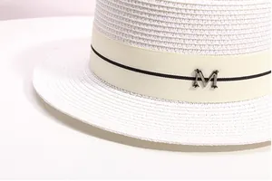 Detailed view of white woven straw hat featuring a striped grosgrain ribbon and metal M buckle