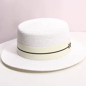 Detail of white boater hat with striped ribbon and silver metal M logo ornament