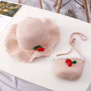 Detail of pink straw sun hat and matching crossbody bag with woven cherry accents