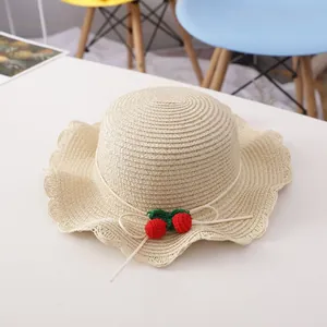 Detail of a wavy edge straw sun hat with crochet cherries and a delicate ribbon bow