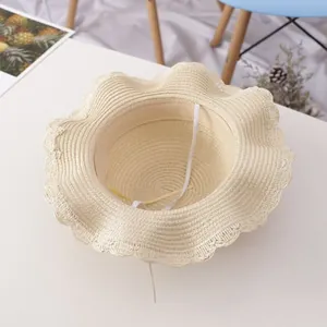 Detail view of beige straw hat with wavy brim, featuring sweatband and elastic wind rope