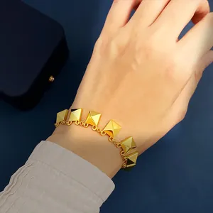 Elegant 18K gold plated bracelet featuring pyramid rivets and tassels on a model wrist