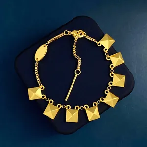 Detail of 18K gold plated box chain bracelet featuring pyramid studs and lobster clasp