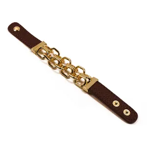 Dettaglio del bracciale in pelle marrone scuro con catena in metallo dorato e bottoni